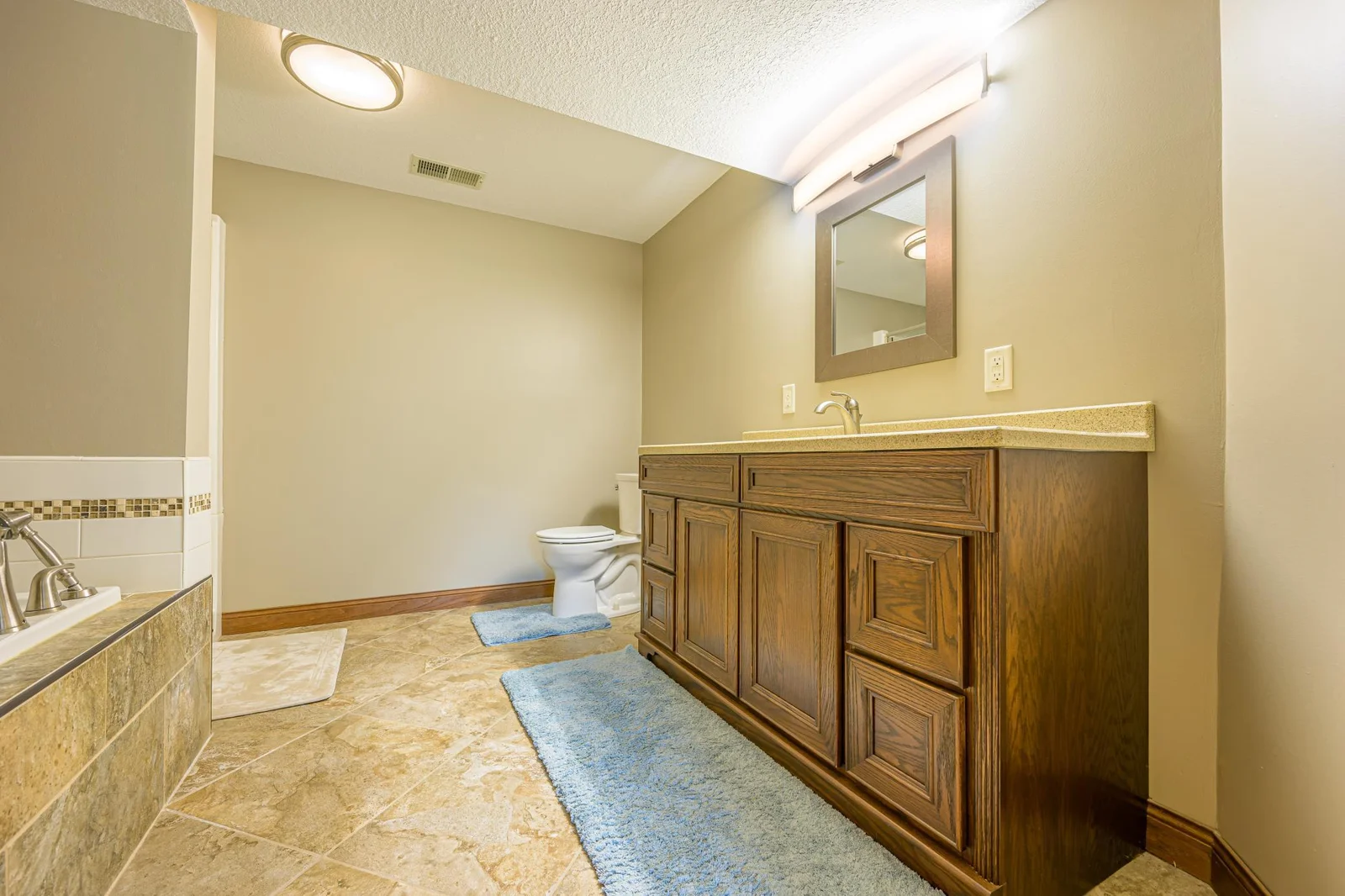 The lower level bathroom features tile flooring, a whirlpool tub with a tile surround, and a separate walk-in shower.
