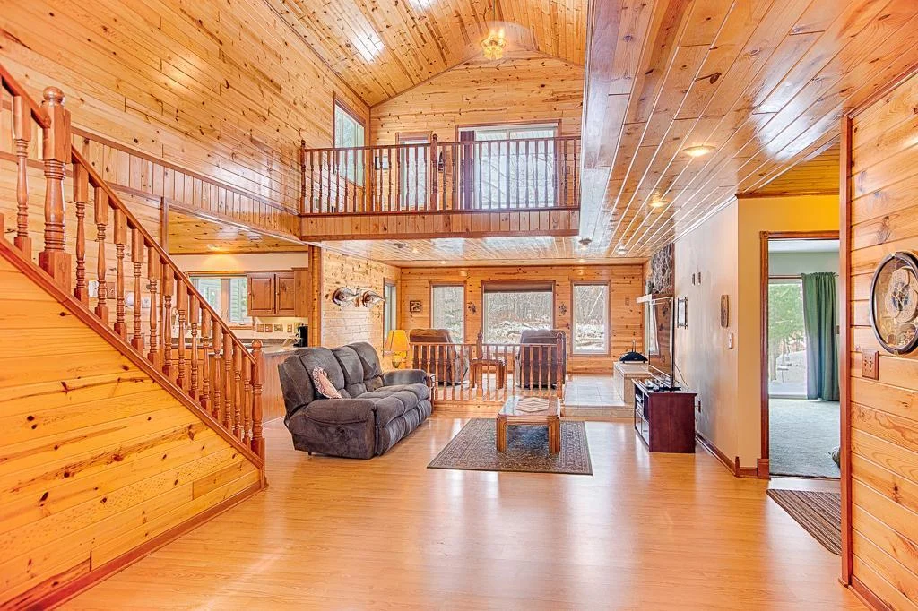 A look at this stunning and massive tongue & groove/vaulted ceiling living room space, featuring the upper level balcony that wraps around this whole living room space and includes excellent creek-side views from both up and downstairs!