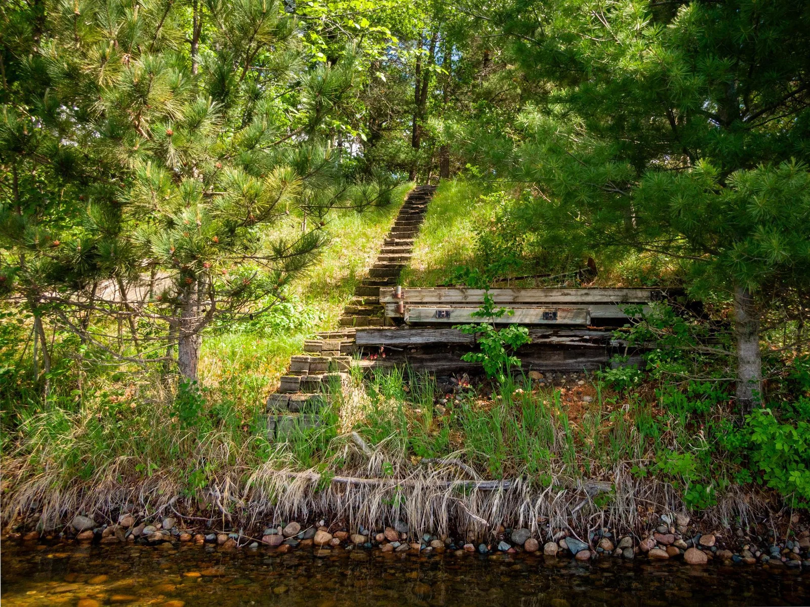 A stairway leads to this rocky, sandy shoreline with crystal blue water.