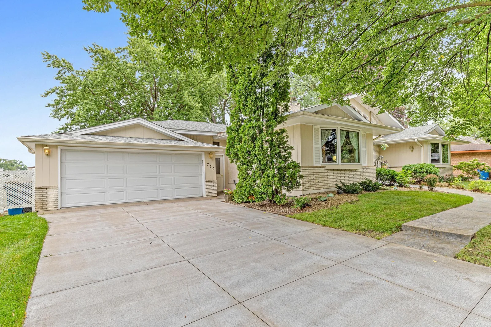 Welcome Home! Concrete driveway, stamped concrete walk, brick and wood exterior