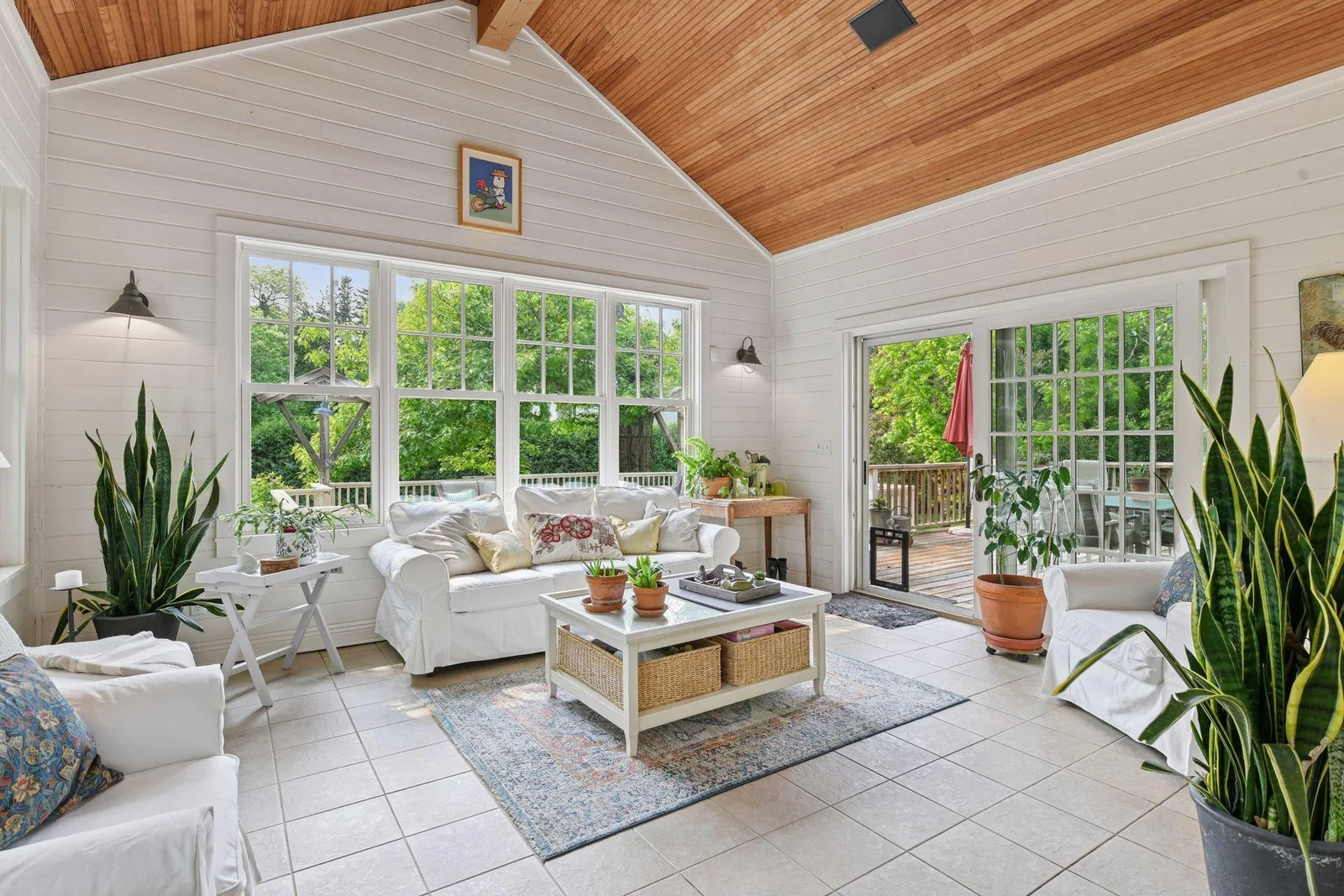 Light and bright four seasons porch with in floor heat, views of the lush outdoor space, and access to the large back deck