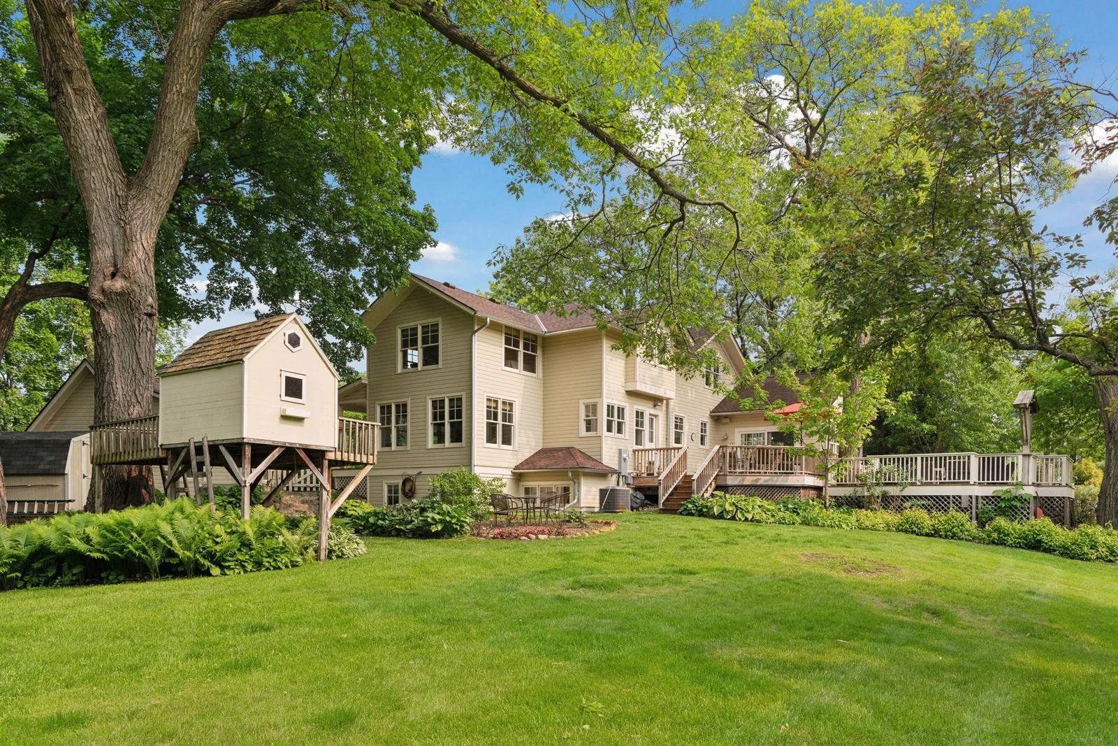 Expansive backyard with a large lawn and charming playhouse ideal for easy indoor/outdoor living and entertaining