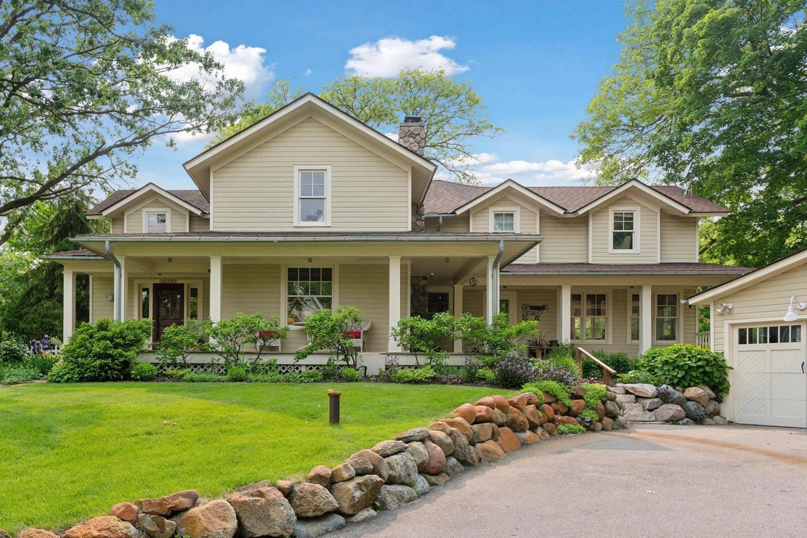 Inviting wrap-around front porch nestled among lush landscaping