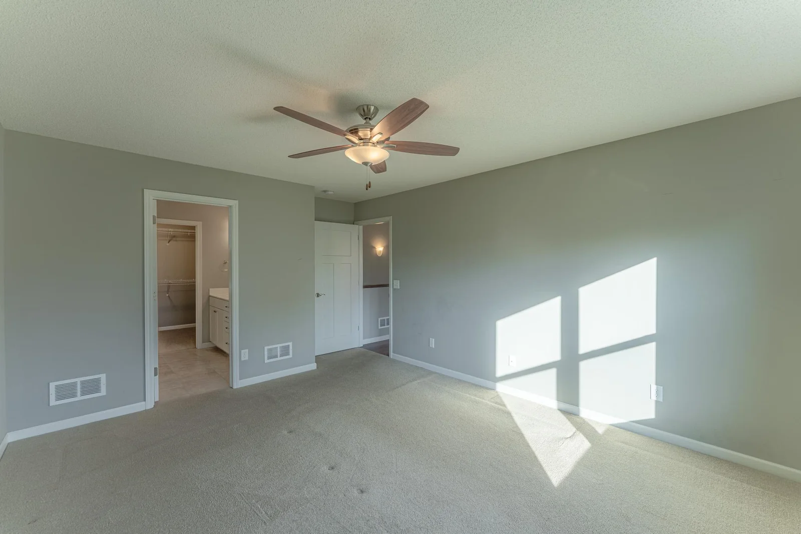 Primary bedroom featuring a private ensuite bath and a walk-in closet.