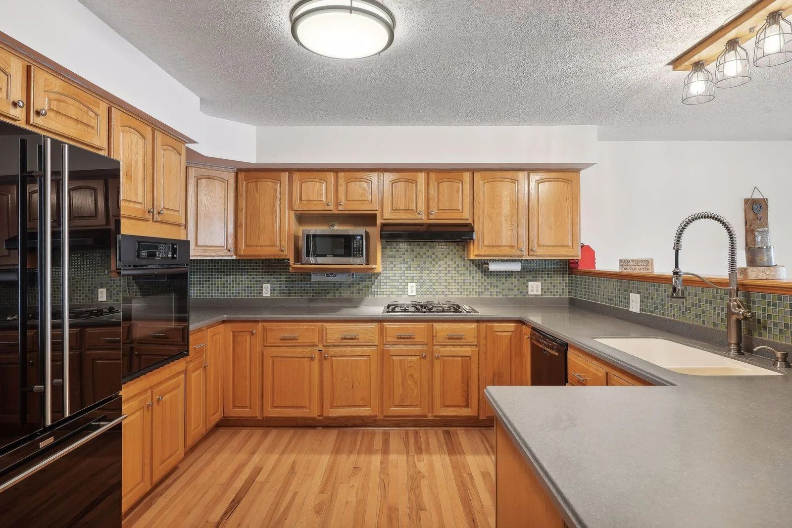 Large spacious kitchen with quartz tops, gas cook top, upgraded appliances, and Hickory floors.