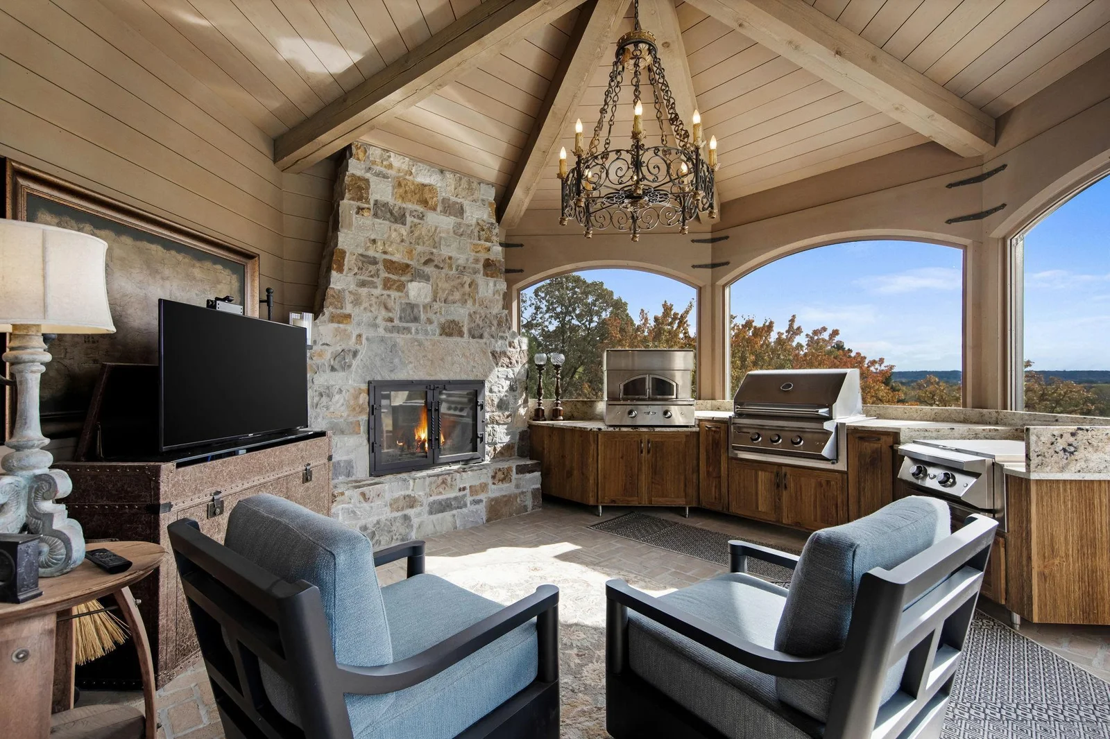 Step into the enchanting screened porch, complete with a stunning fireplace, perfect for year-round enjoyment. Featuring a built-in pizza oven, grill, and flat top. For added convenience, a hidden TV easily moves back into the cabinet space.