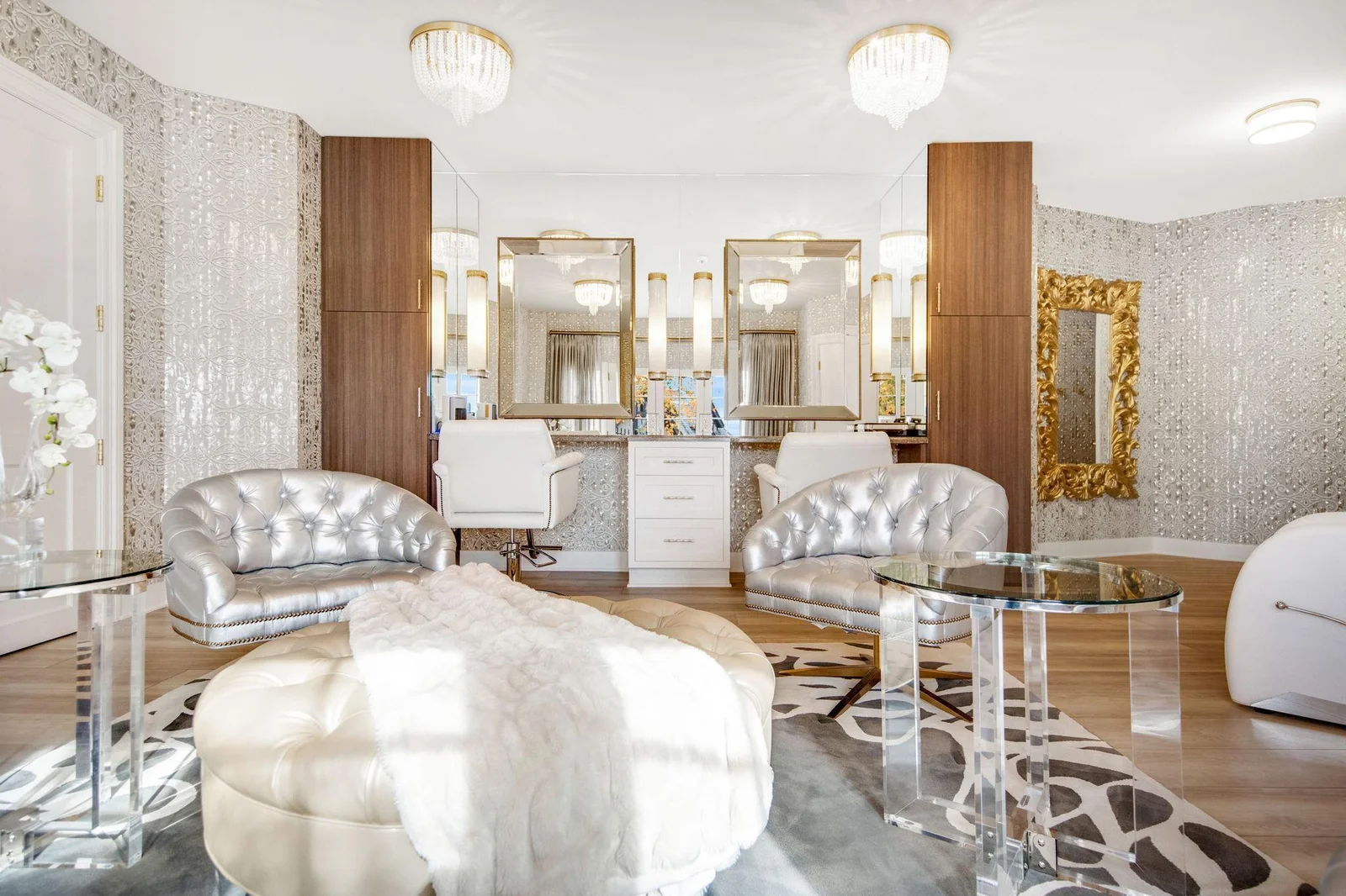Each station is equipped with ample counter space for tools and products, ensuring everything is easily accessible. The large mirrors enhance the sense of space and allow for detailed work, reflecting the beautiful lighting throughout the room.