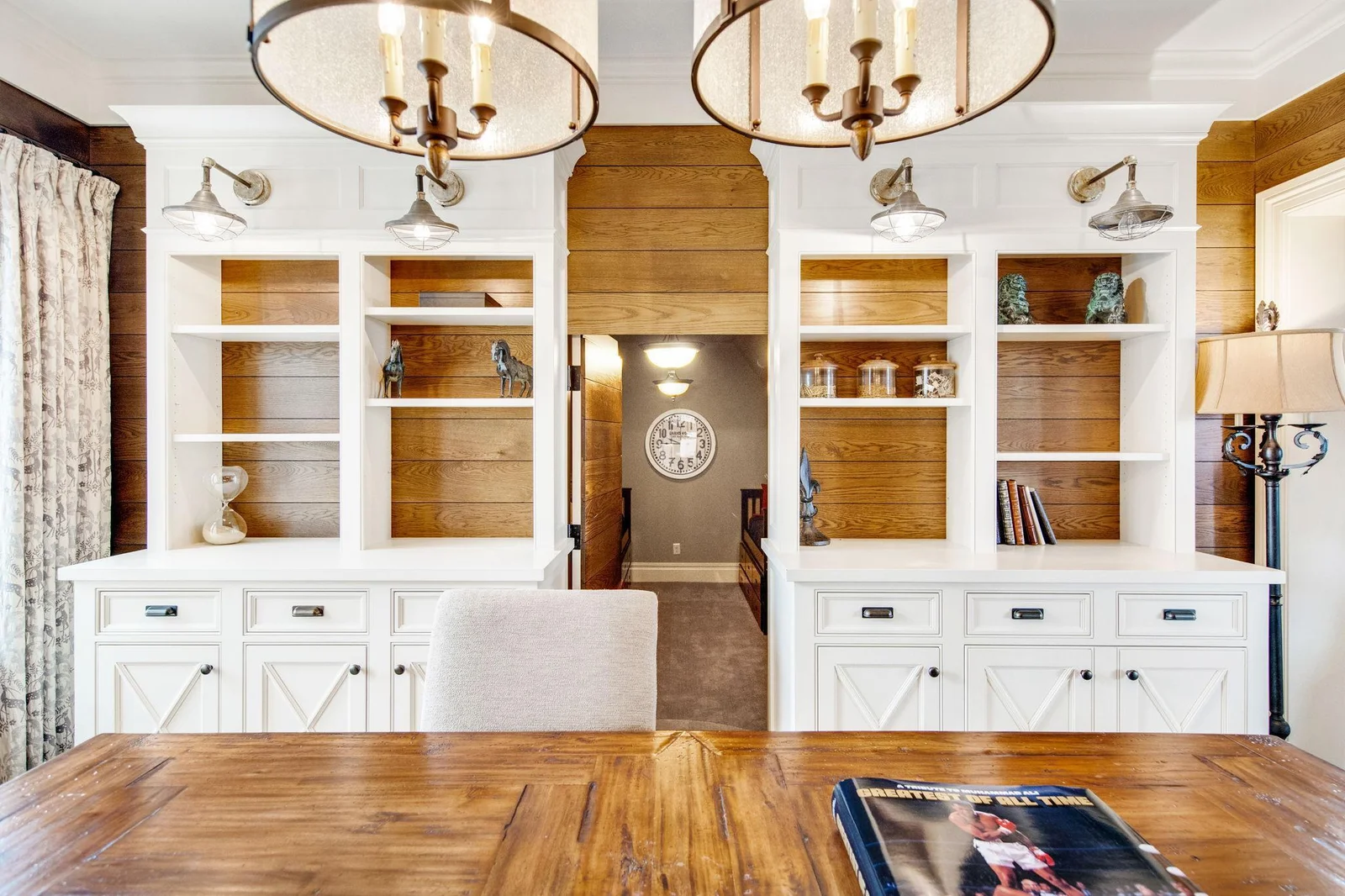 In a delightful twist, the upper-level office space features built-in shelves that not only serve as elegant storage but also conceal a hidden door leading to a secret room.