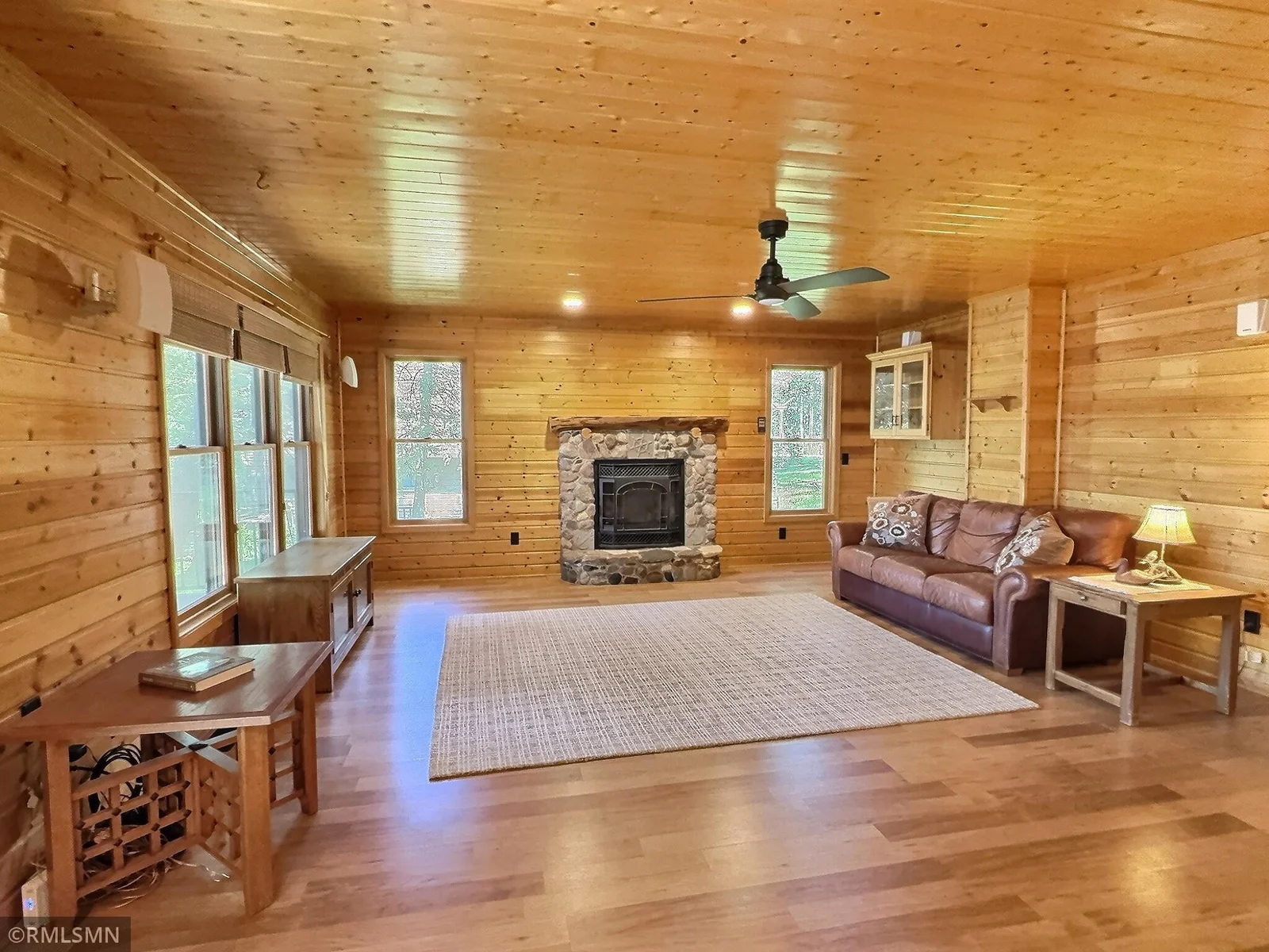 Warmed by a gas fireplace with rock accent, the living room is surrounded with knotty cedar walls and ceiling.