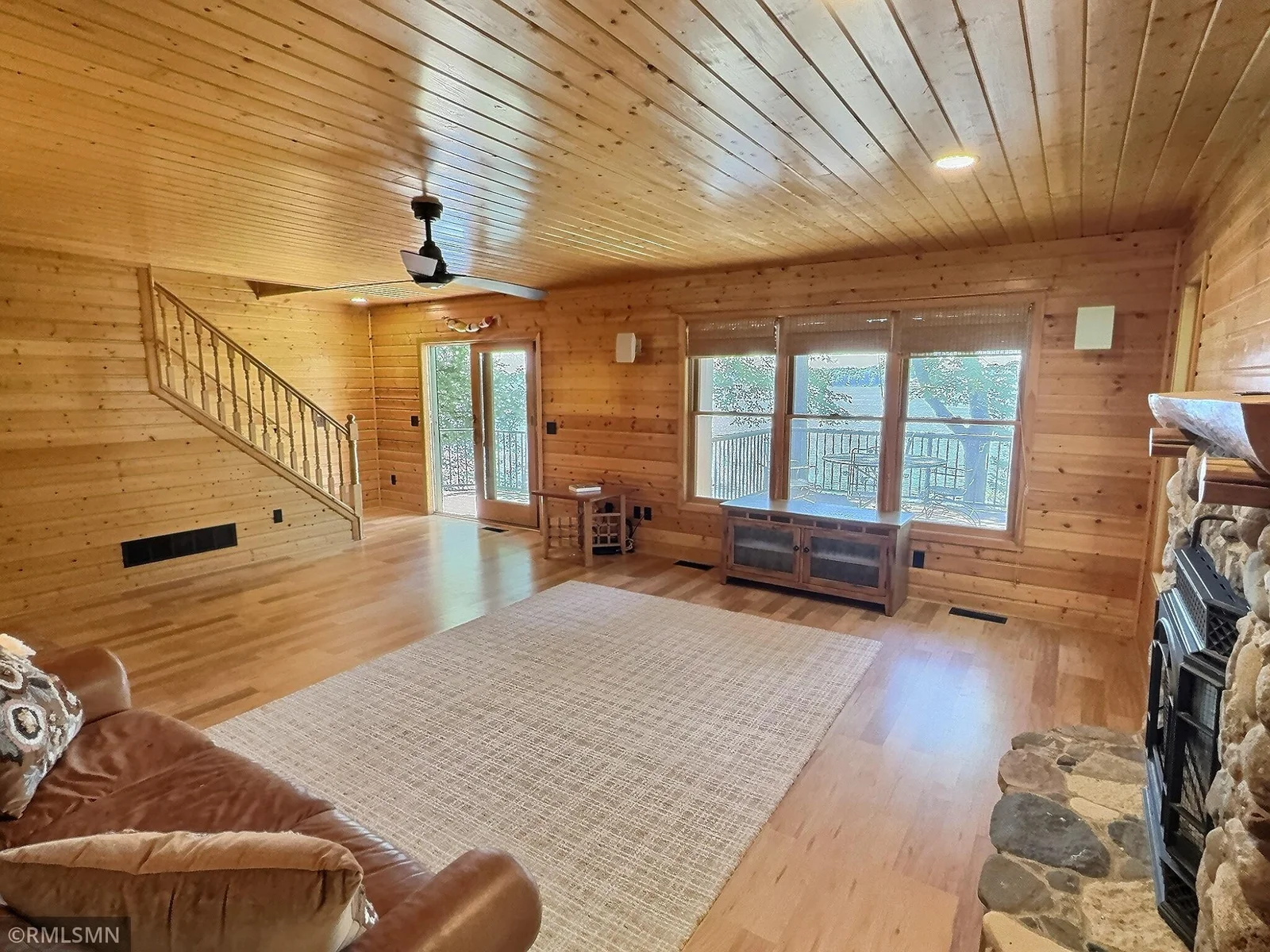 A sliding glass door opens to the expansive lakeside deck while the staircase leads to the upper level.
