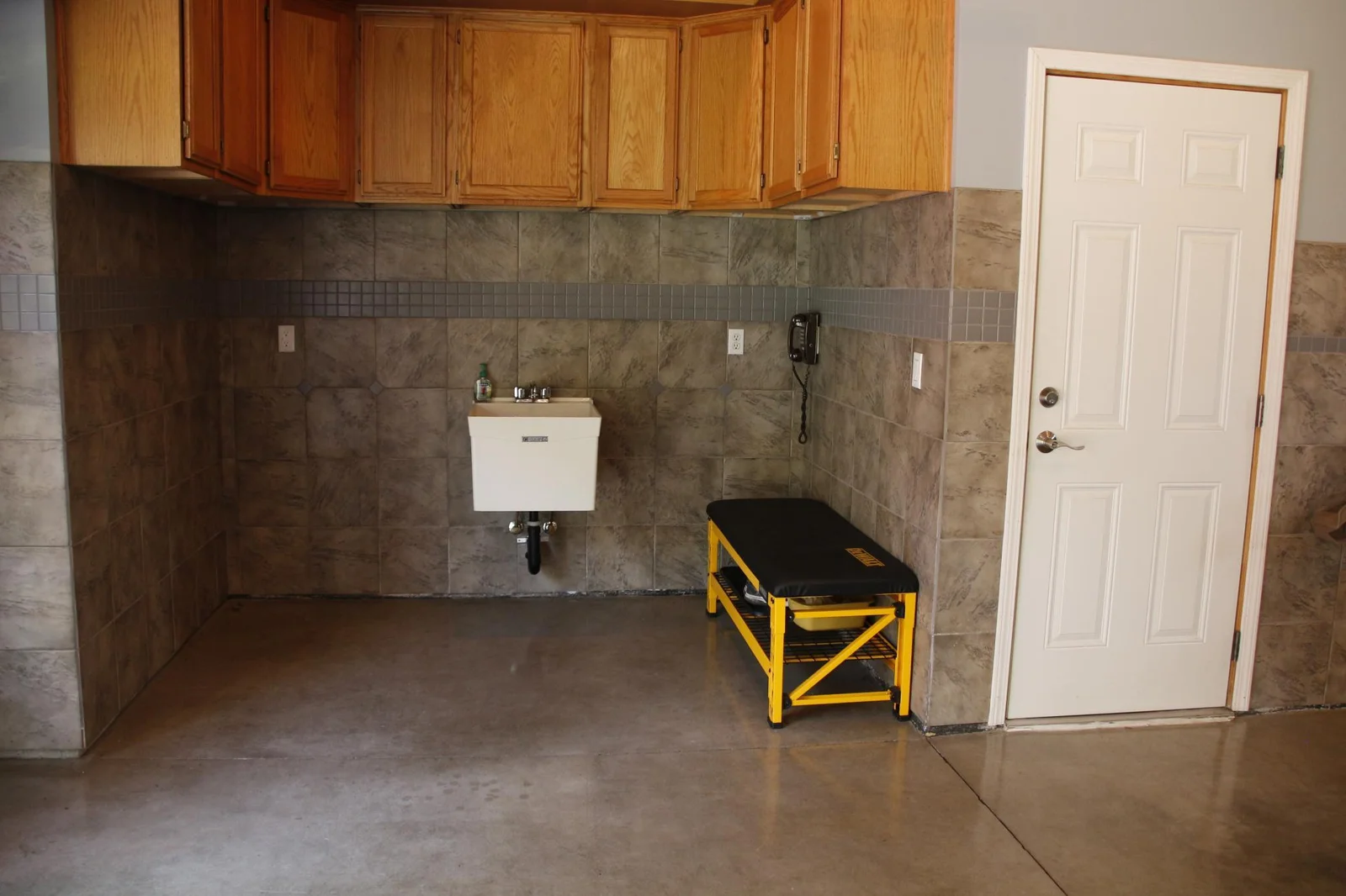 Workspace nook in garage with cabinets and utility tub