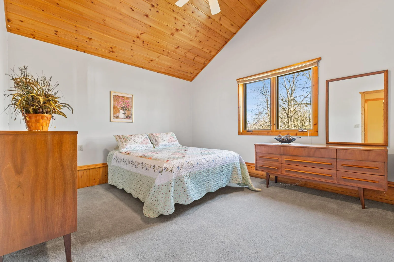 Step into this cozy bedroom, where rustic charm meets modern comfort. The knotty pine vaulted ceiling adds a unique and warm touch, creating an inviting atmosphere that makes this space truly special.
