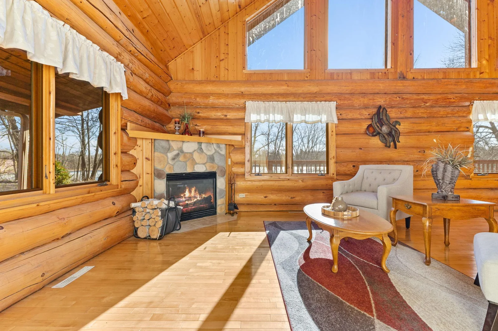 The large windows offer breathtaking views of Lake Berthiaume, creating a serene and picturesque setting. The corner fireplace adds warmth and charm, while the vaulted ceiling enhances the sense of  grandeur.