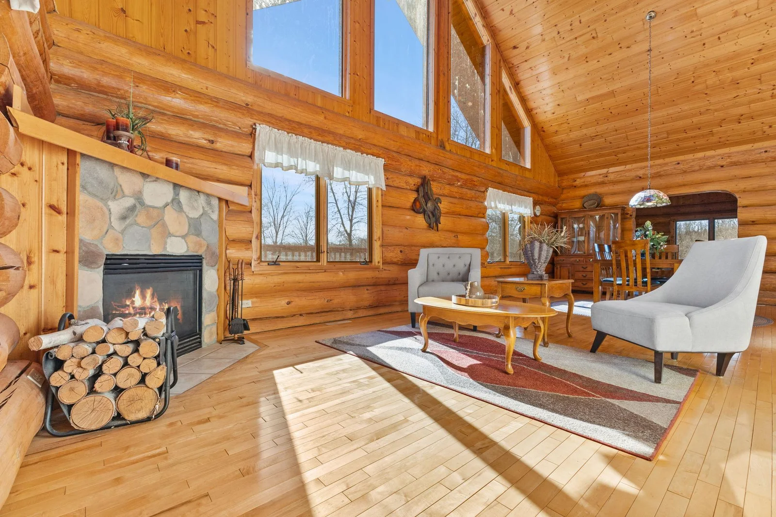 This living room boasts a cozy corner fireplace, perfect for gathering around on chilly evenings. The vaulted ceiling adds a sense of grandeur, while the floor-to-ceiling windows flood the space with natural light and offer breathtaking views.