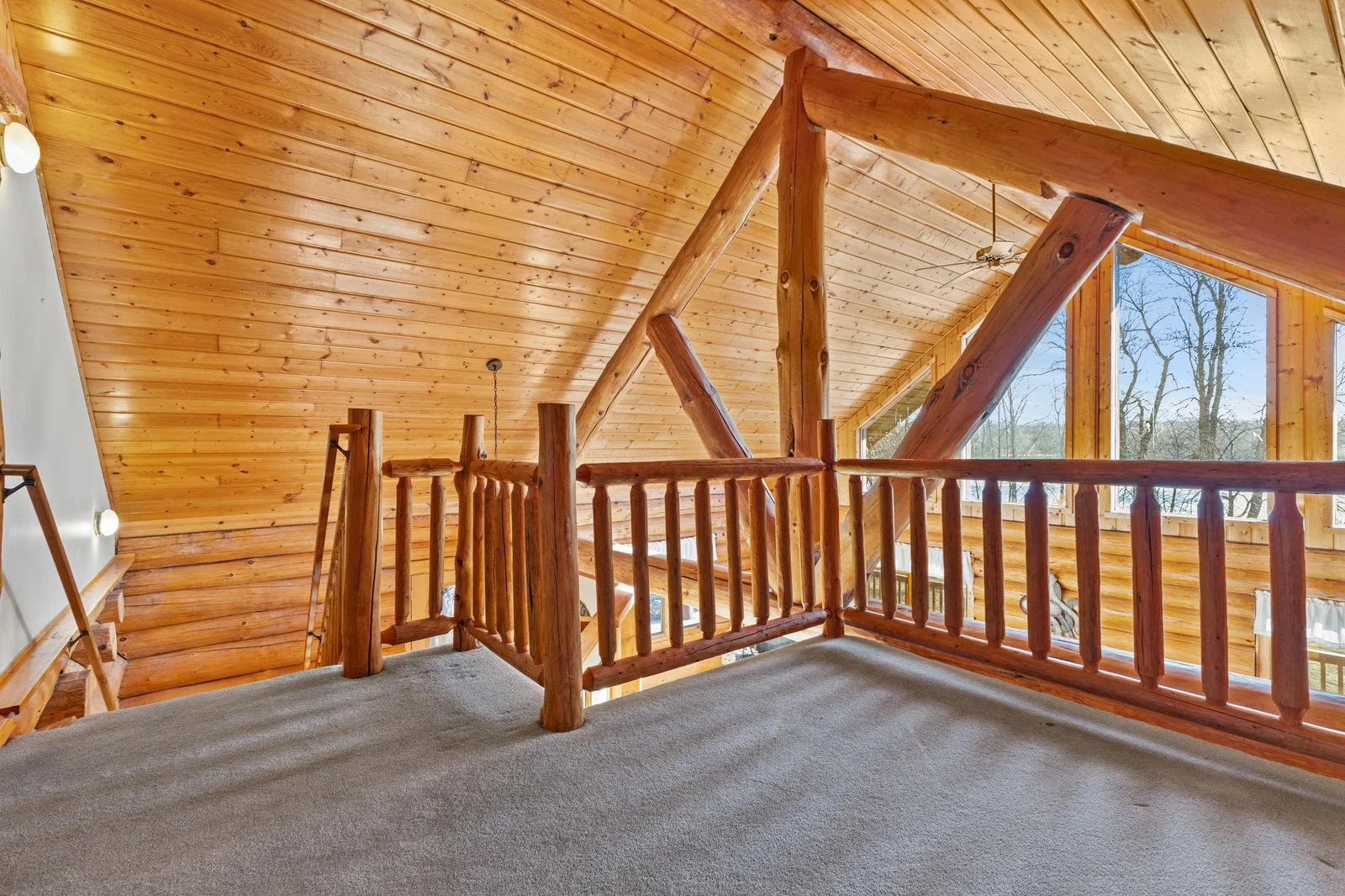 Relax and unwind in this charming loft sitting area, offering breathtaking views of the lake. The log vaulted ceiling adds a rustic touch, creating a warm and inviting atmosphere. A great place to read a book.