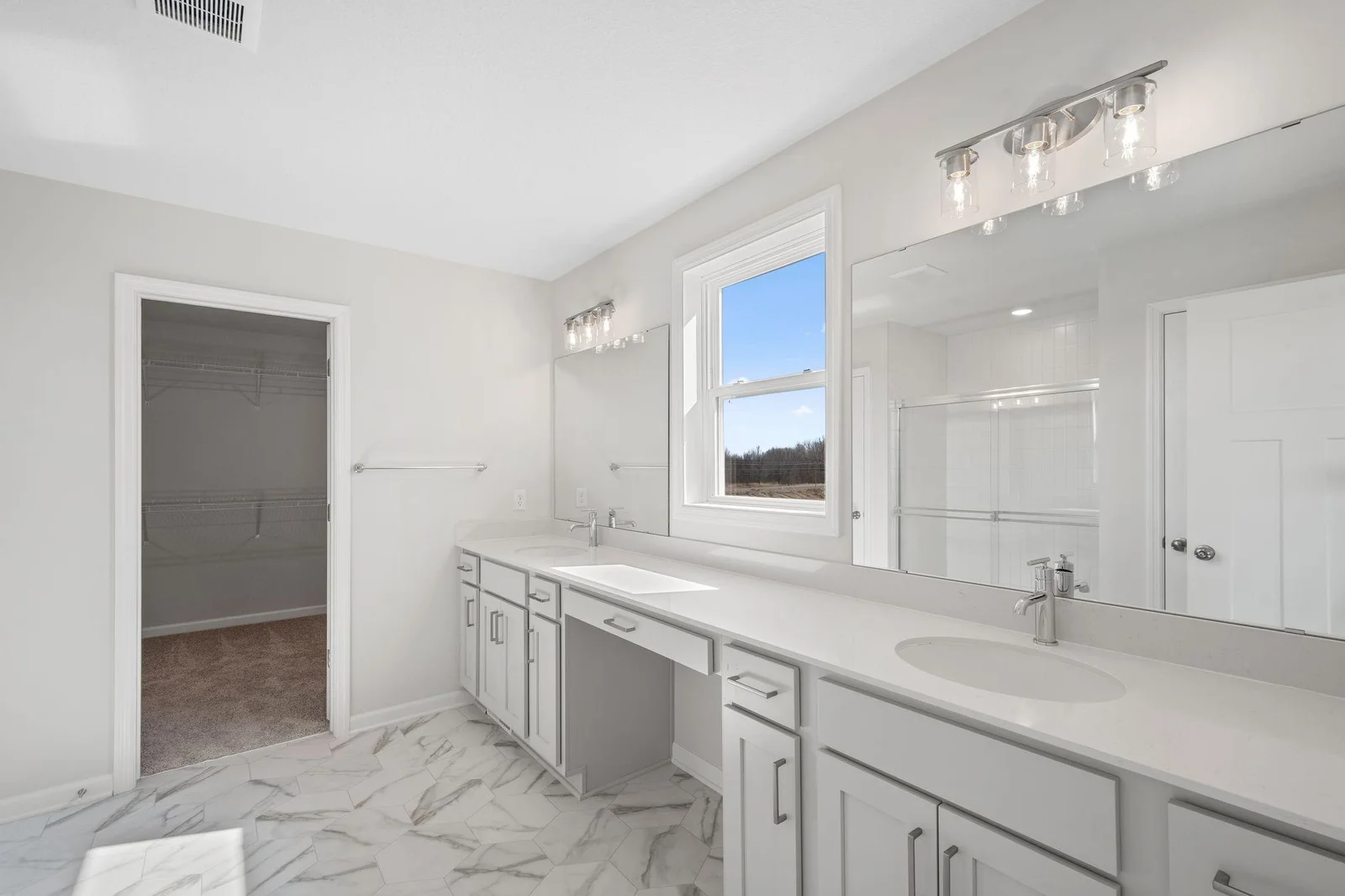 Step into the luxurious owner's bath with dual sinks, upgraded tile shower walls, and spacious walk-in closet.