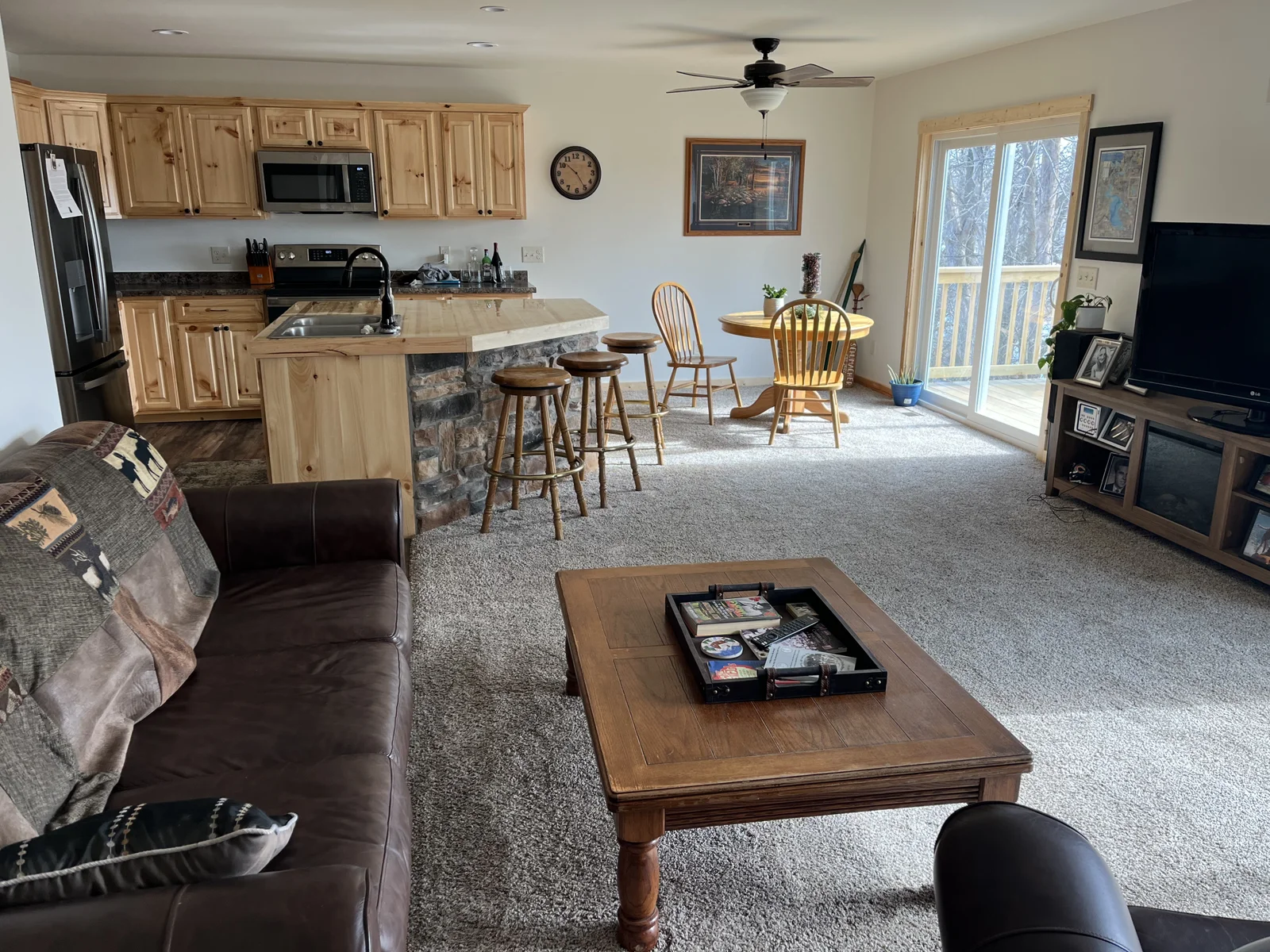 The living room with the kitchen and small dining area with additional deck access.