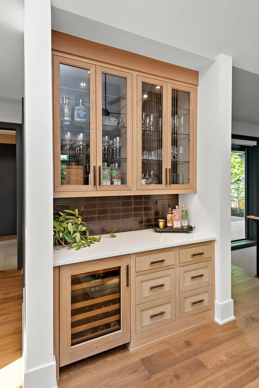 This Designer Spirits Nook features flush inset cabinetry, polished tiled backsplash, and KitchenAid wine chiller.
