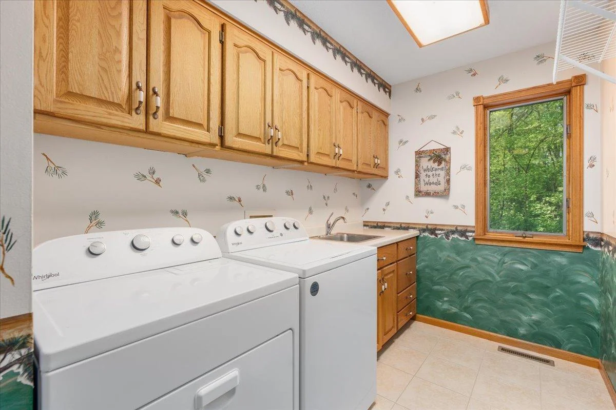 Main floor laundry room with storage, tiled floor and laundry sink area