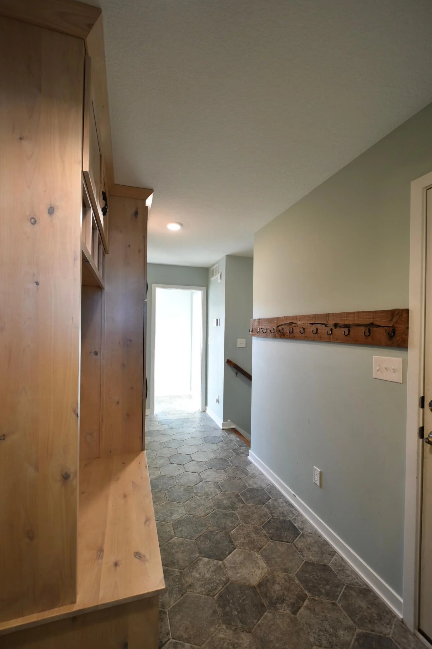 Large mudroom with built-ins & coat hanger. Stairs to basement