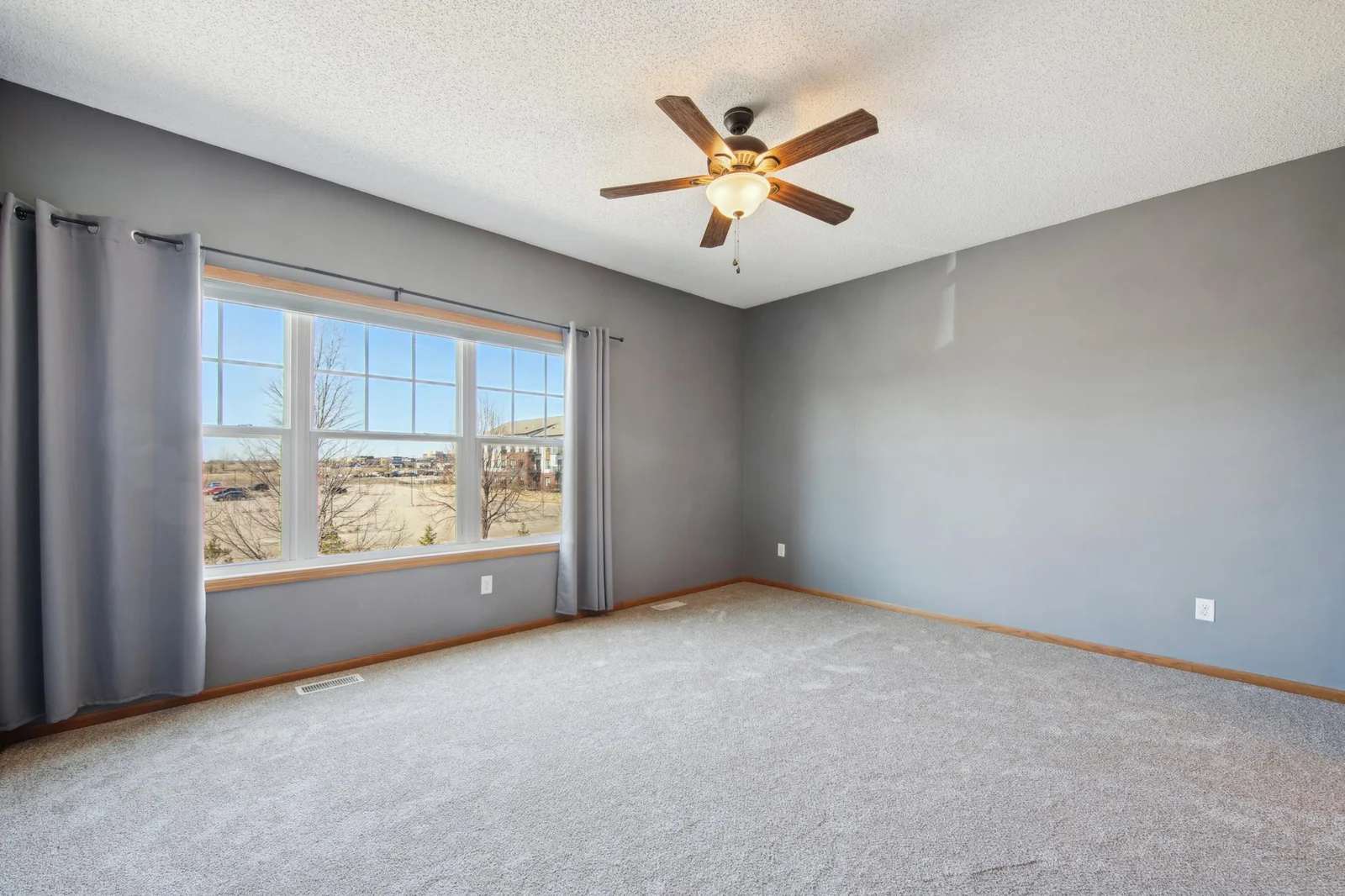 Large owners suite with new carpet and an expansive window filling the room with natural light.