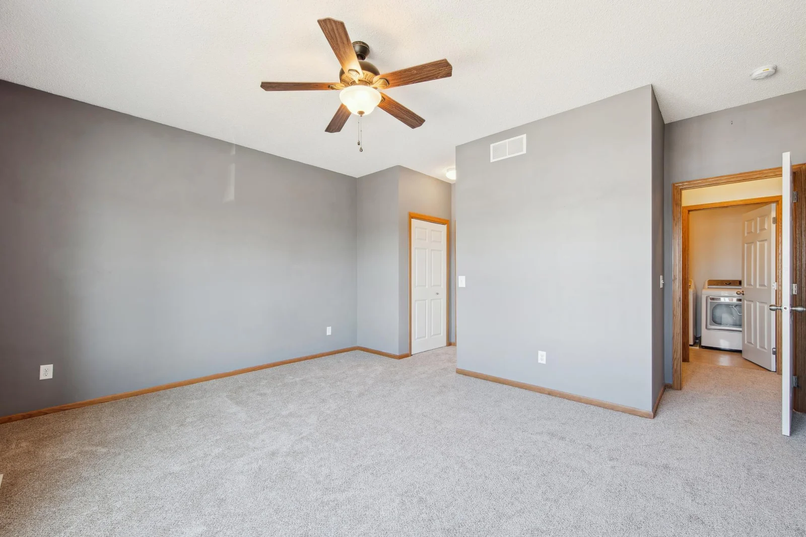 Spacious owners suite with a large fan, walk-in closet and private full bathroom