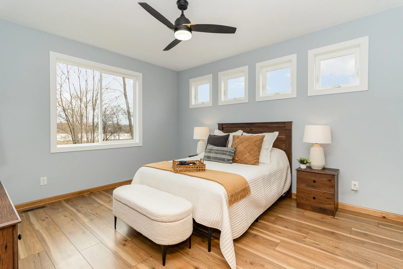 Beautiful primary suite bedroom offers views of the lake, and privacy height windows let in the sunlight.
