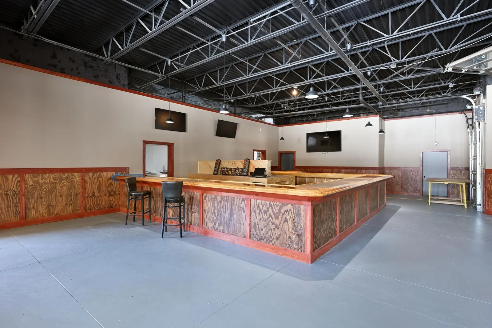 Photo of the large bar, and entrances to the kitchen area. The space has also been updated with many new light fixtures including stylish pendant lighting.