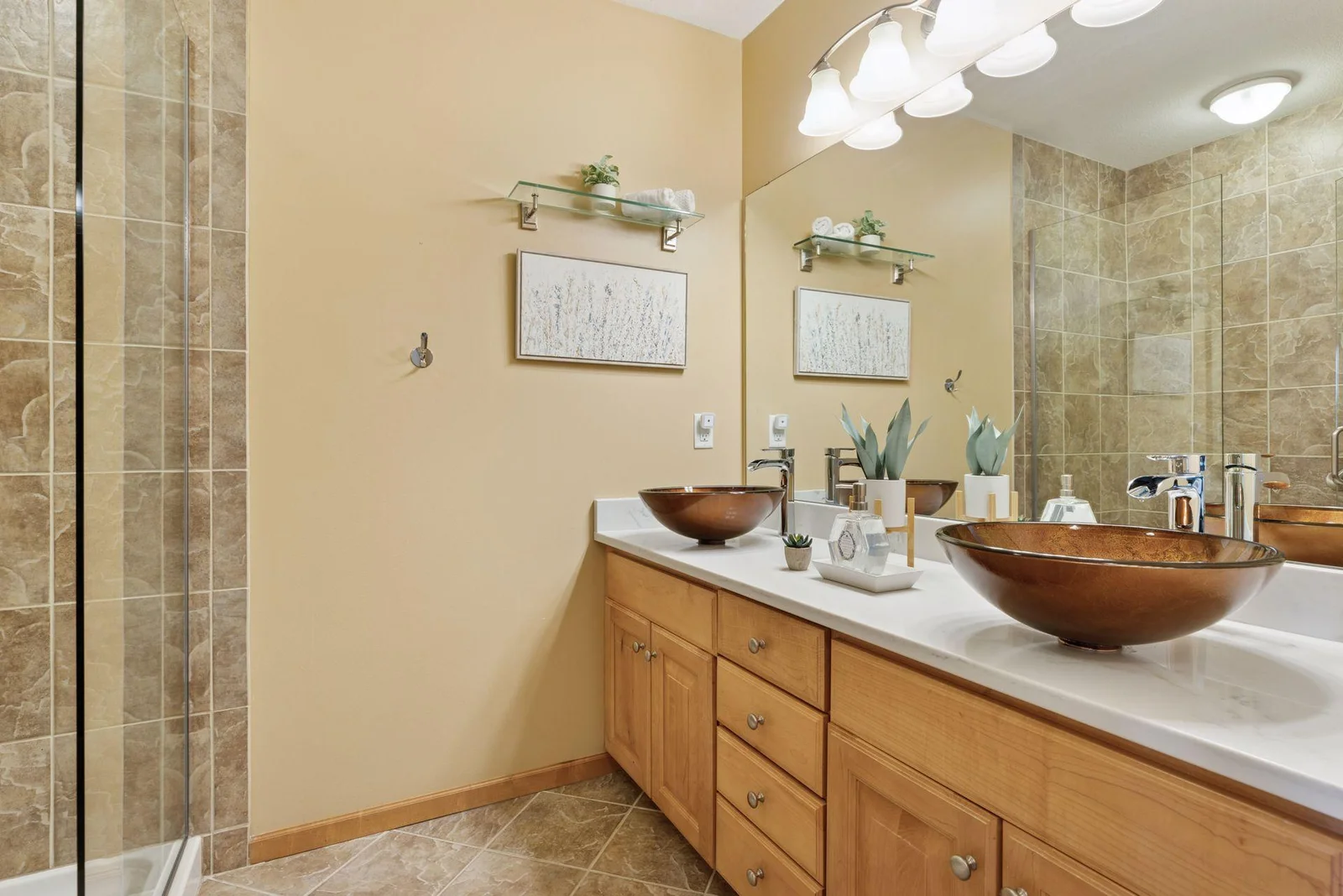 Primary bath updates include understated elegance with a dual bowl sink, classic tile, a step-in shower, and cabinetry.