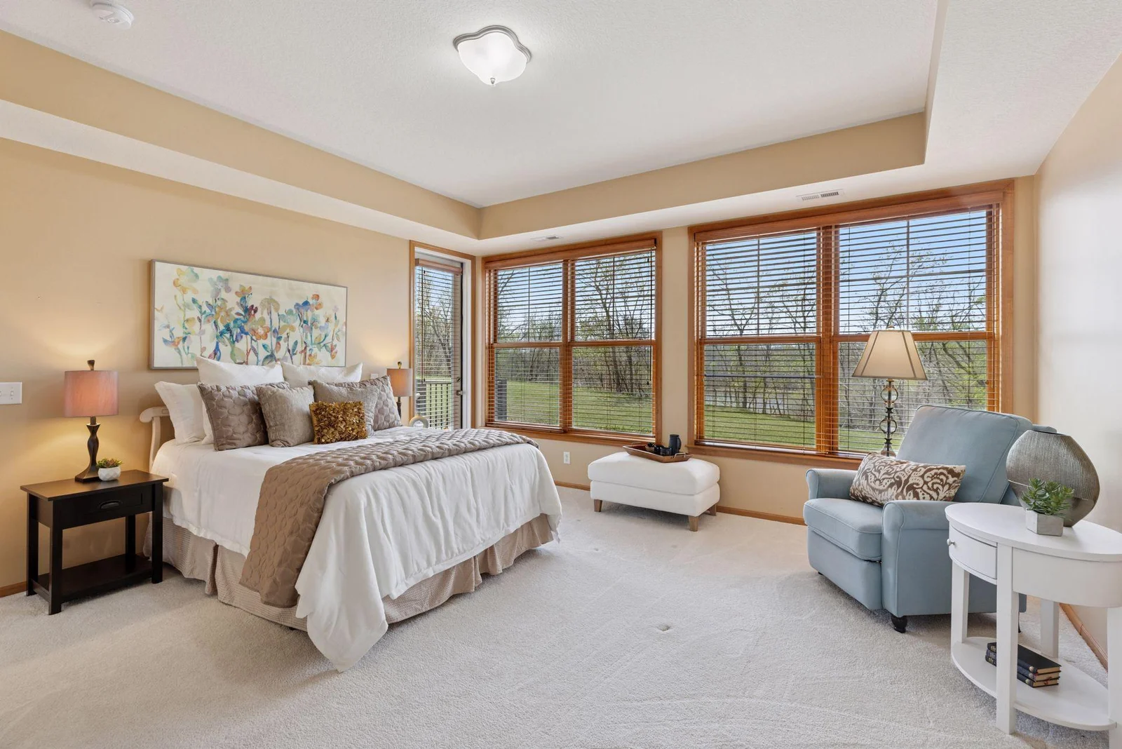 A wall of windows in the Primary Bedroom ensuite, including a door that steps right out to the patio. Notice the beautiful wood blinds!