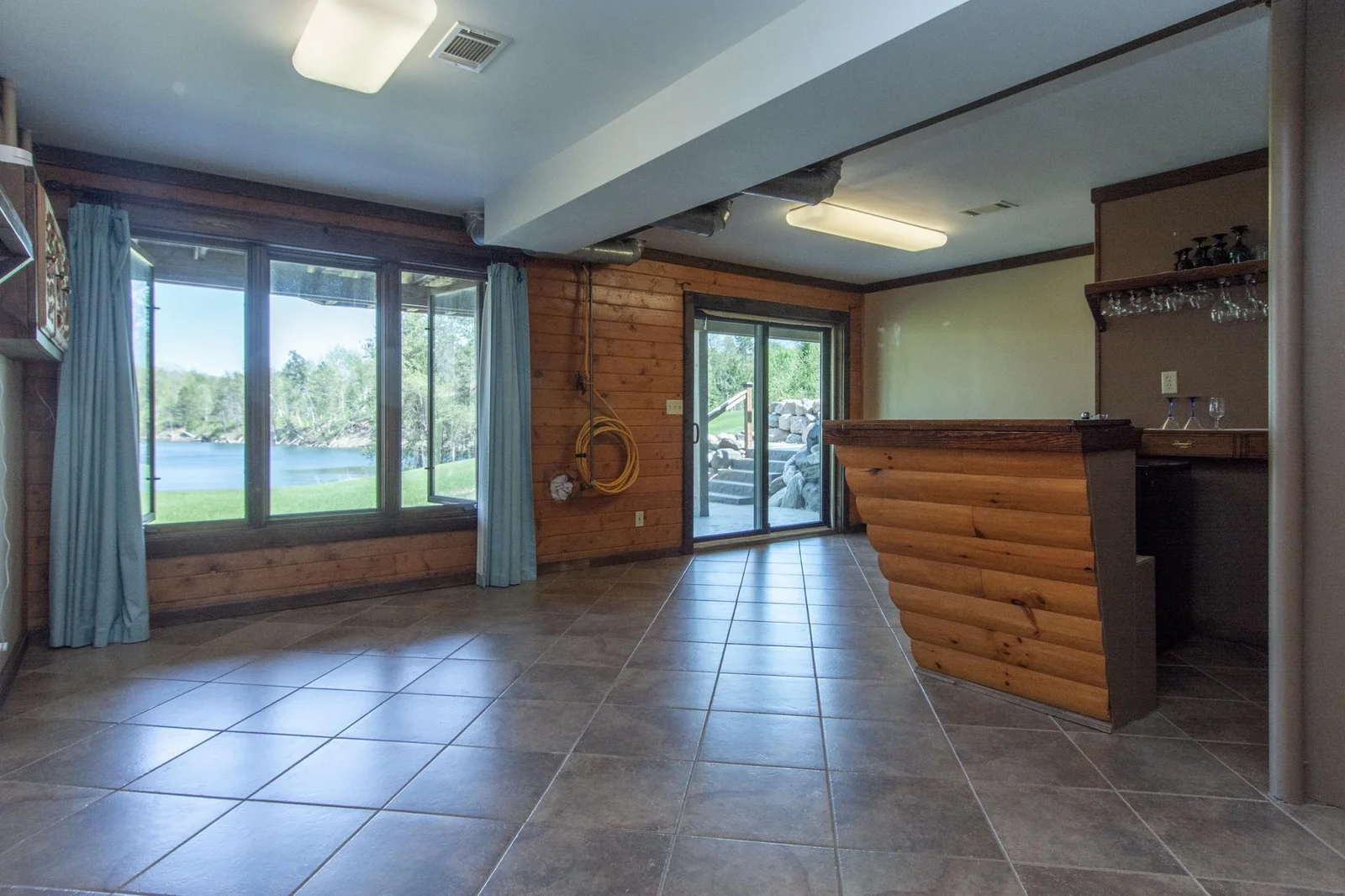 The family room has a tile floor, an east-facing window, a bar, and a sliding glass door to the back patio.