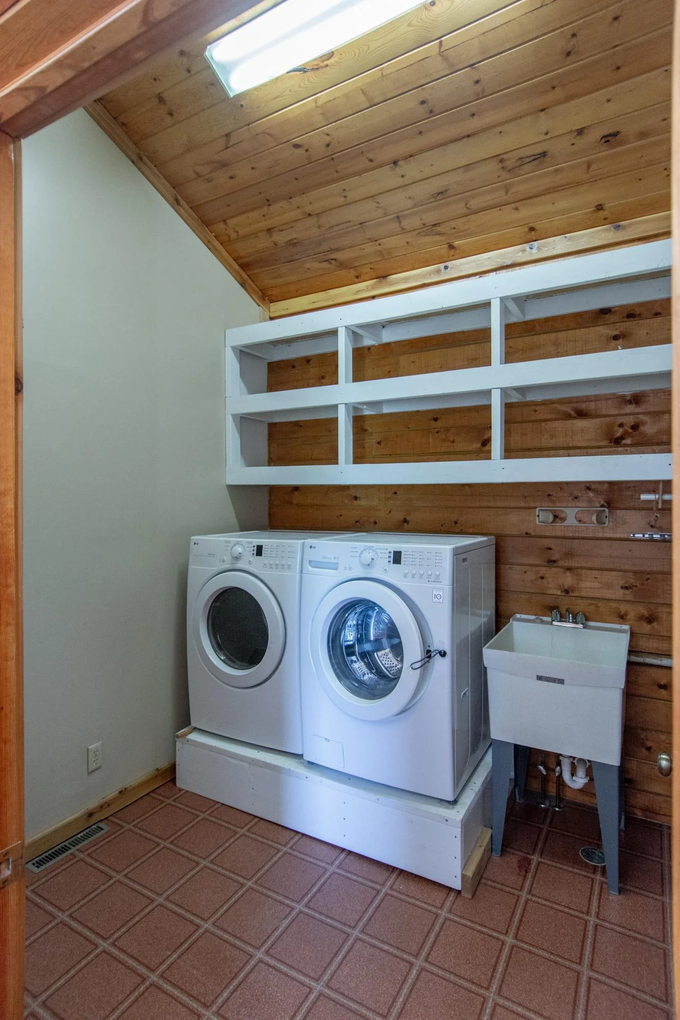 The laundry room has a linoleum floor, a vaulted ceiling, and a sink.
