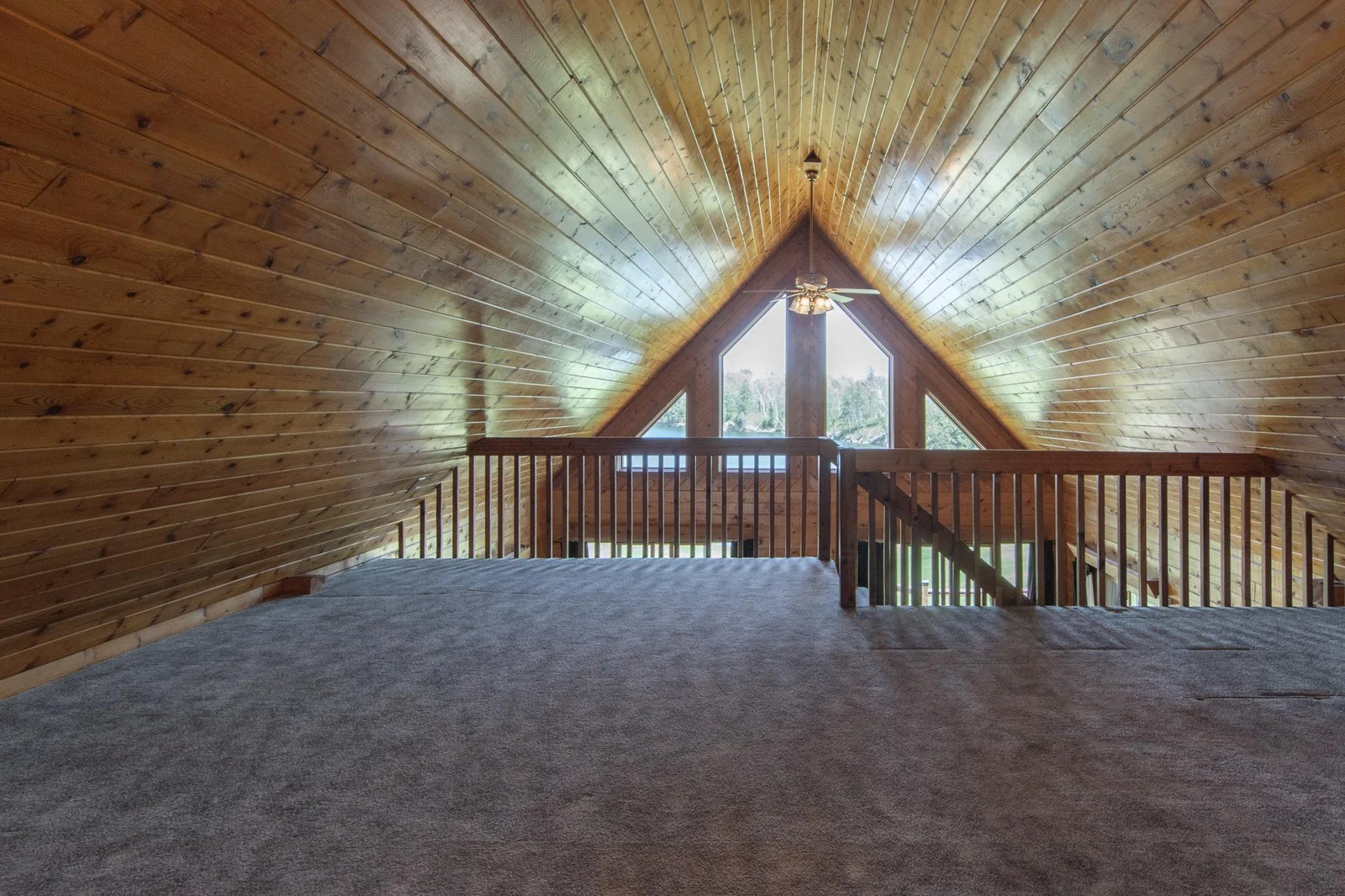 The loft has a carpeted floor, a ceiling fan, and a west-facing window.