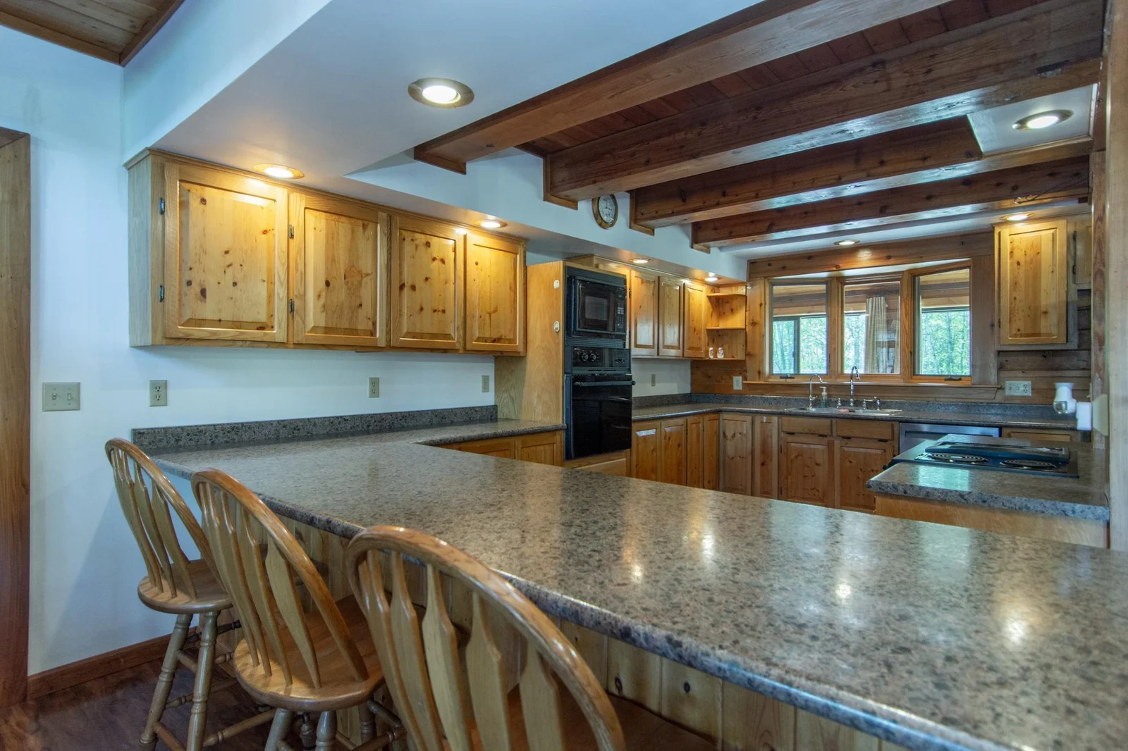 The kitchen has a vinyl floor, knotty pine cabinets, oak trim, a stainless steel fridge and dishwasher, and a west-facing window.