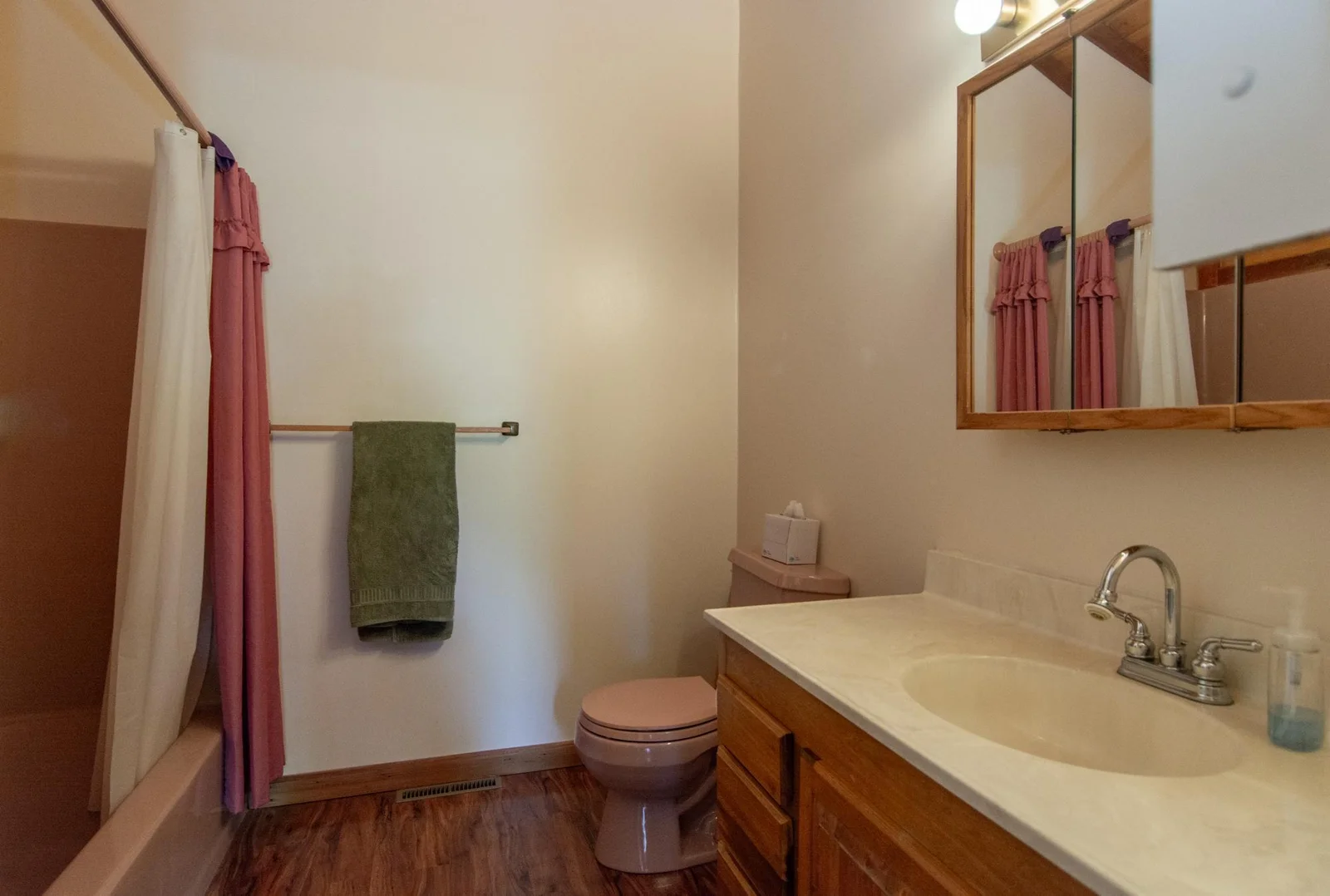 The full primary bathroom has a vinyl floor and a vaulted ceiling.