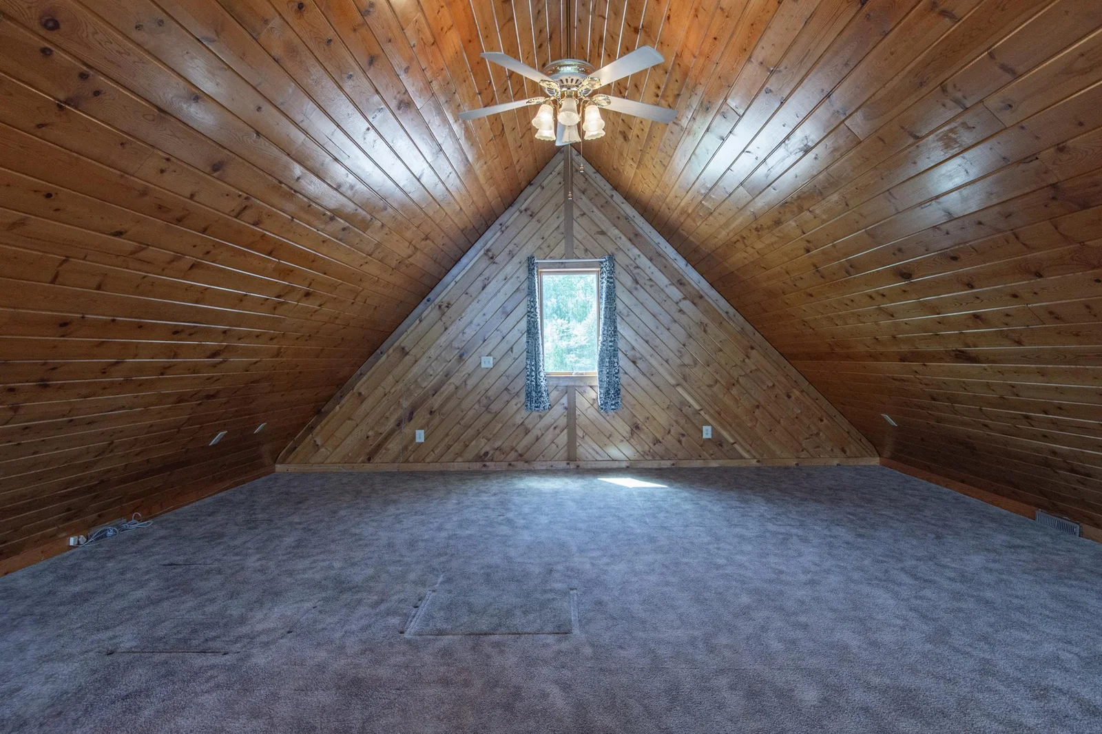 The loft has a carpeted floor, a ceiling fan, and a west-facing window.