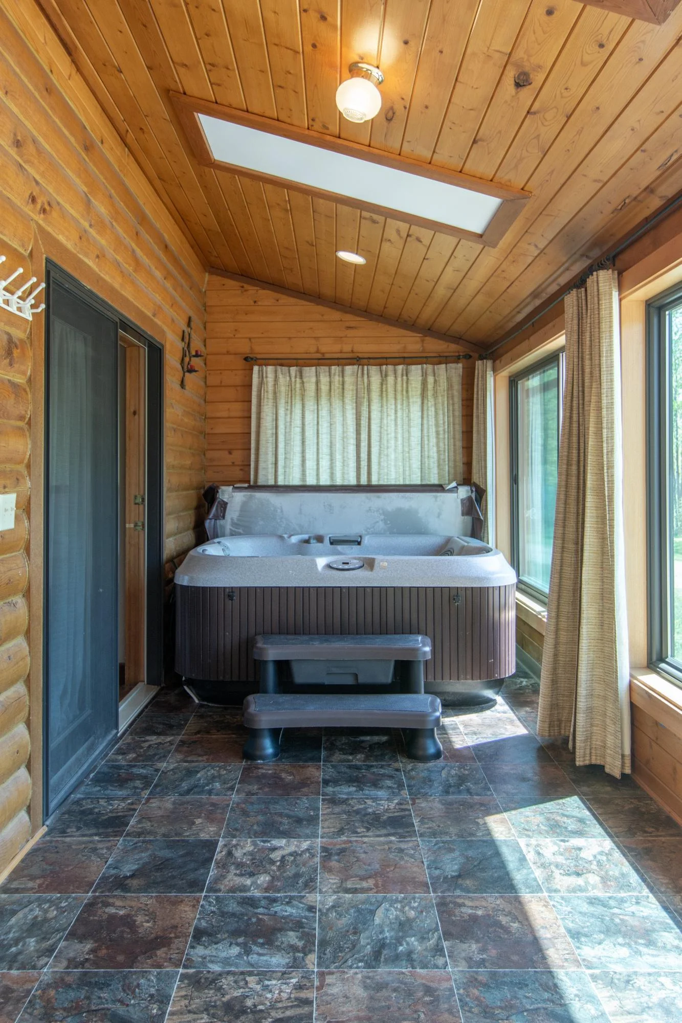 The four-season porch has a linoleum floor, five west-facing windows, a south-facing window, and a hot tub.