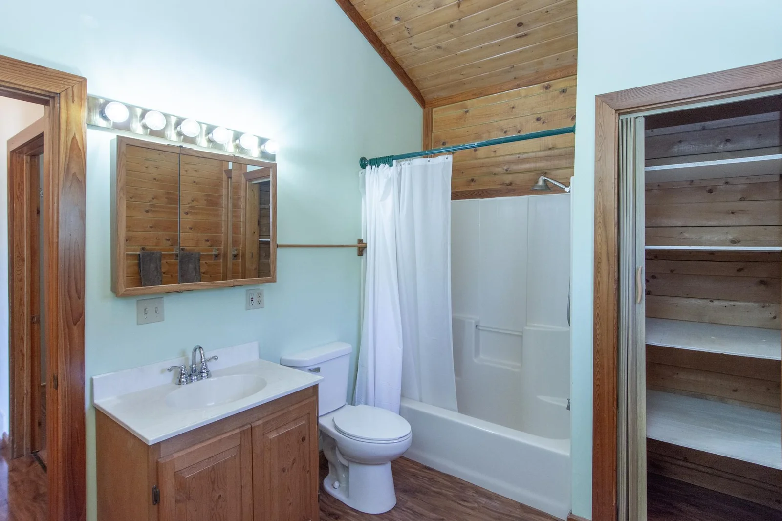 Main floor full bathroom has vinyl floor, a vaulted ceiling, a north-facing window, and a 2x3 ft. closet.