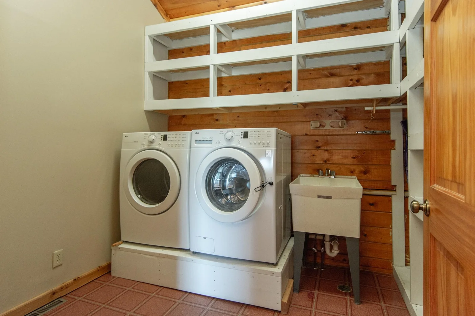 The laundry room has a linoleum floor, a vaulted ceiling, and a sink.