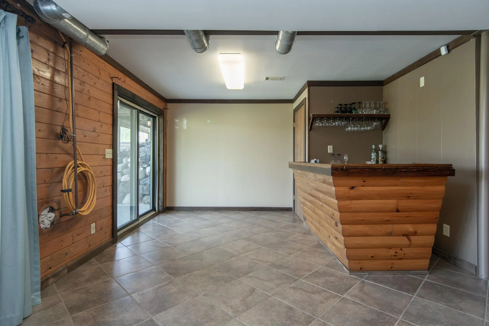 The family room has a tile floor, an east-facing window, a bar, and a sliding glass door to the back patio.