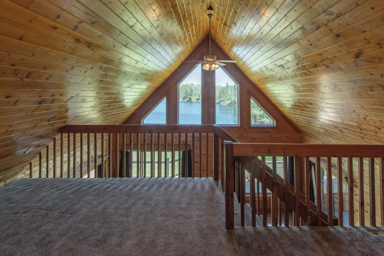The loft has a carpeted floor, a ceiling fan, and a west-facing window.