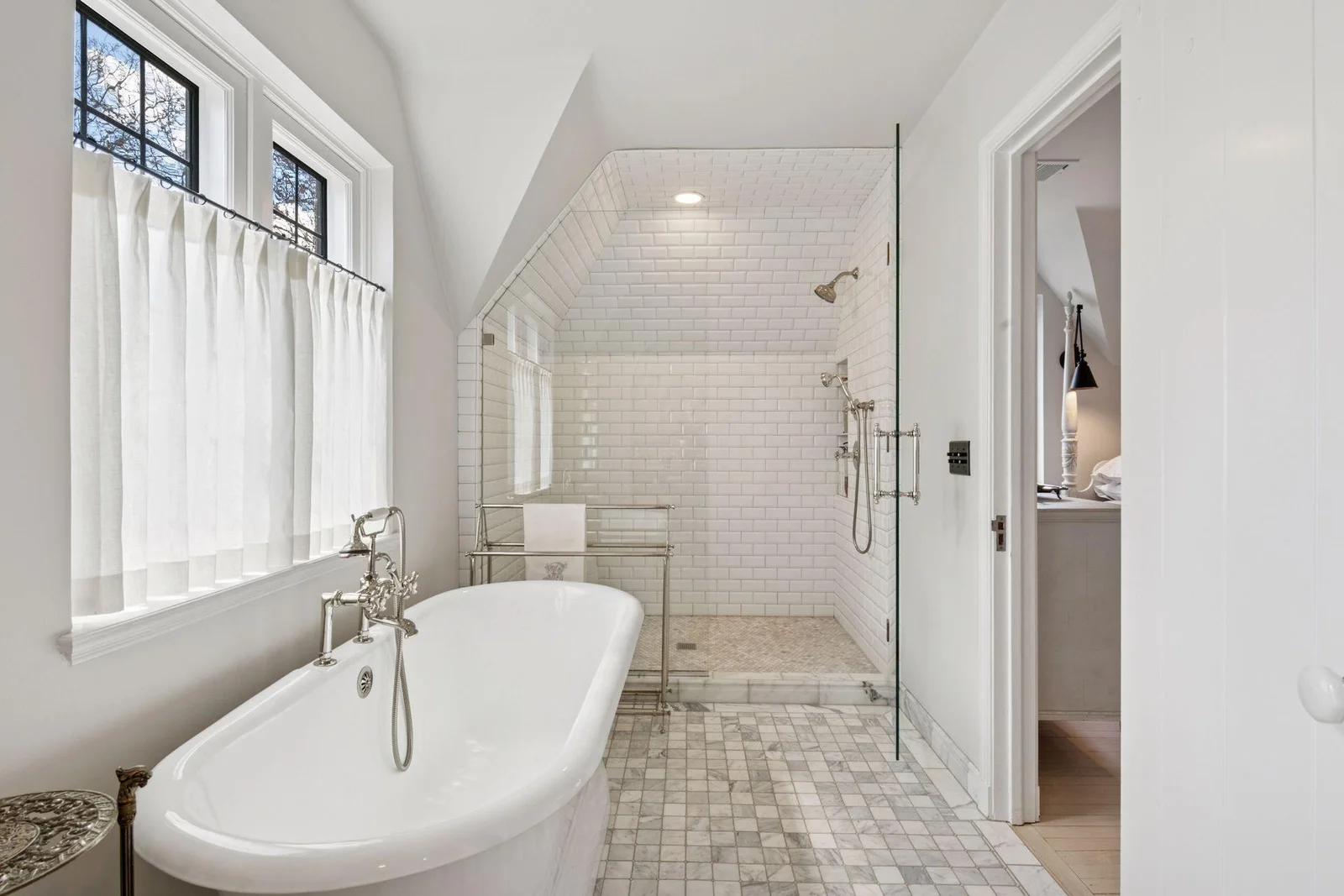Gorgeous primary bath renovation features marble tile, a spacious walk-in shower, an inviting soaking tub, and a double vanity.