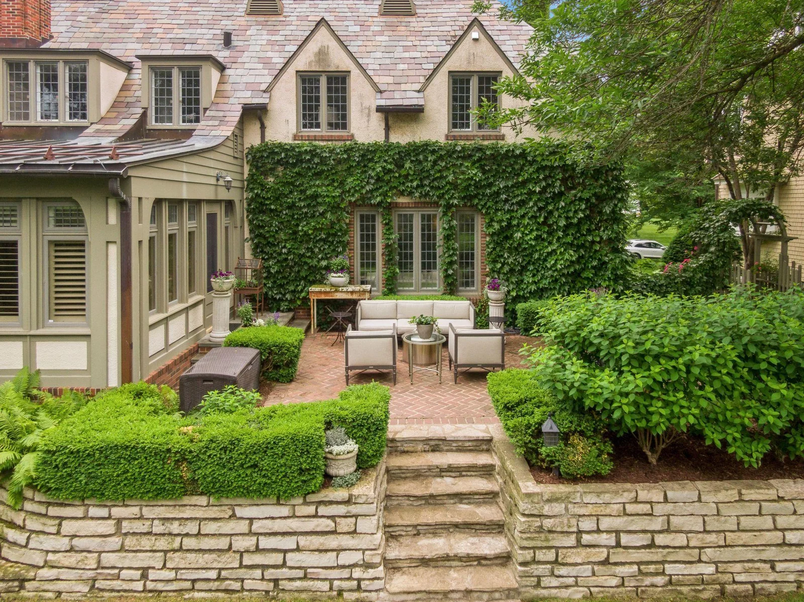 Professionally landscaped with stone retaining walls and steps leading to lower level lawns and hot tub area.