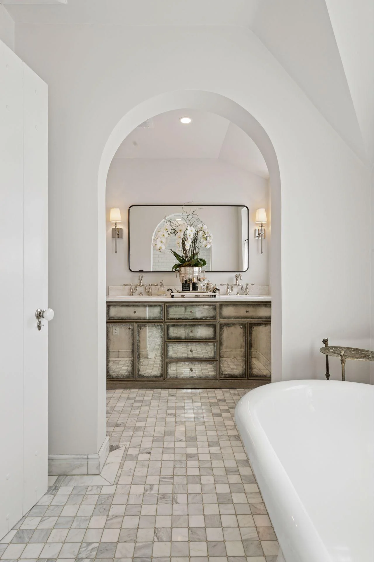 An arched doorway leads to a double vanity in the primary bathroom.