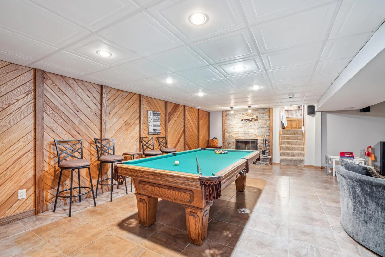 Expansive basement rec room with a floor to ceiling stone fireplace and ample room for entertaining friends and family