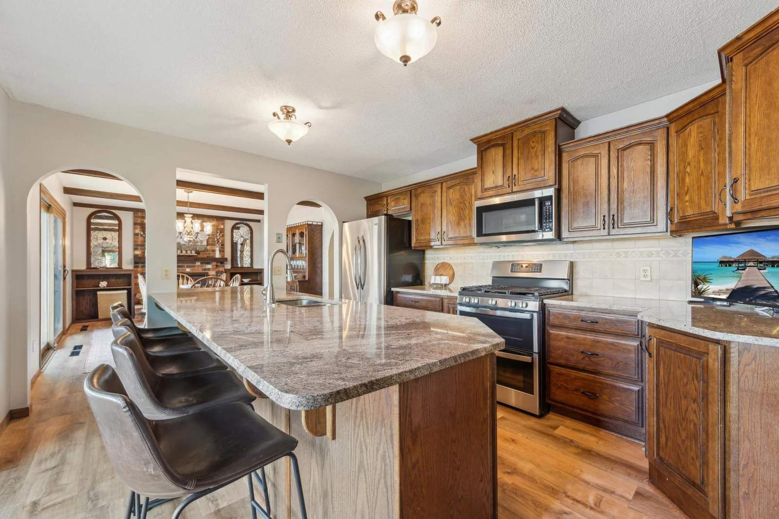 Beautifully designed kitchen with rich wood cabinetry, granite countertops, stainless steel appliances, and a large center island with bar seating.