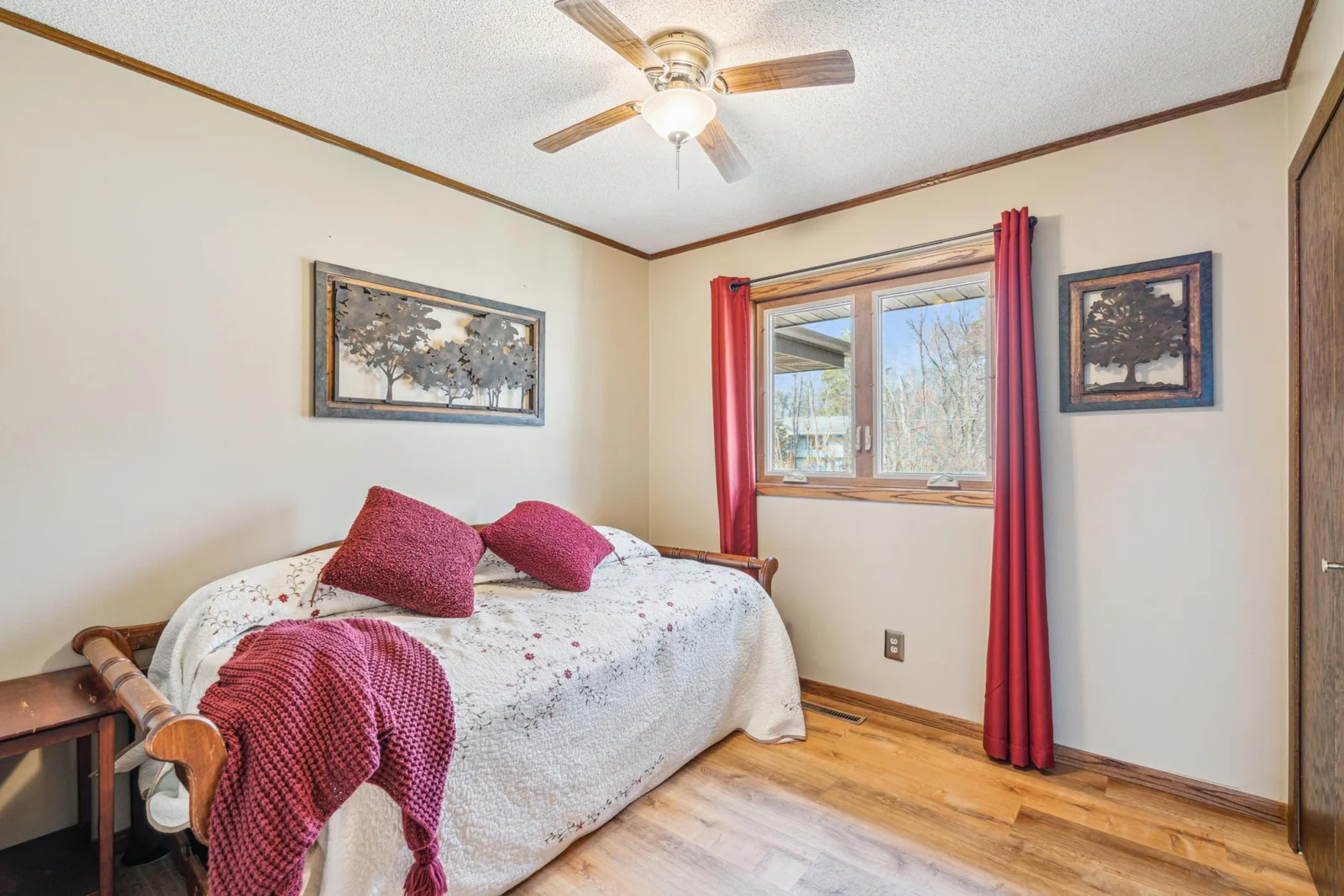 Main level bedroom with a large ceiling fan, gleaming wood like floors and a large closet