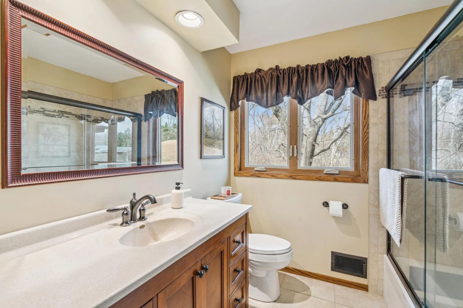 Main level full bathroom with a spacious vanity, tile floors, and elegant tile shower.