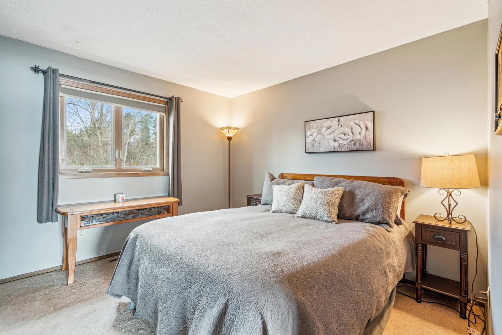 Lower level bedroom with plush carpet and a large window filling the room with natural light.