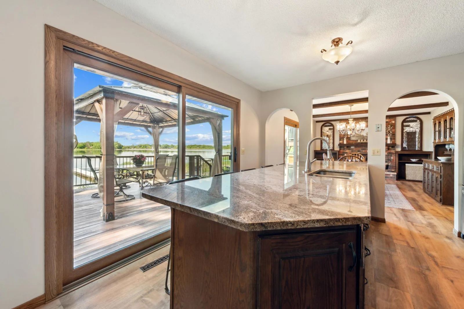 Stunning kitchen island with granite countertops, stainless steel appliances, and panoramic lake views through oversized sliding doors.